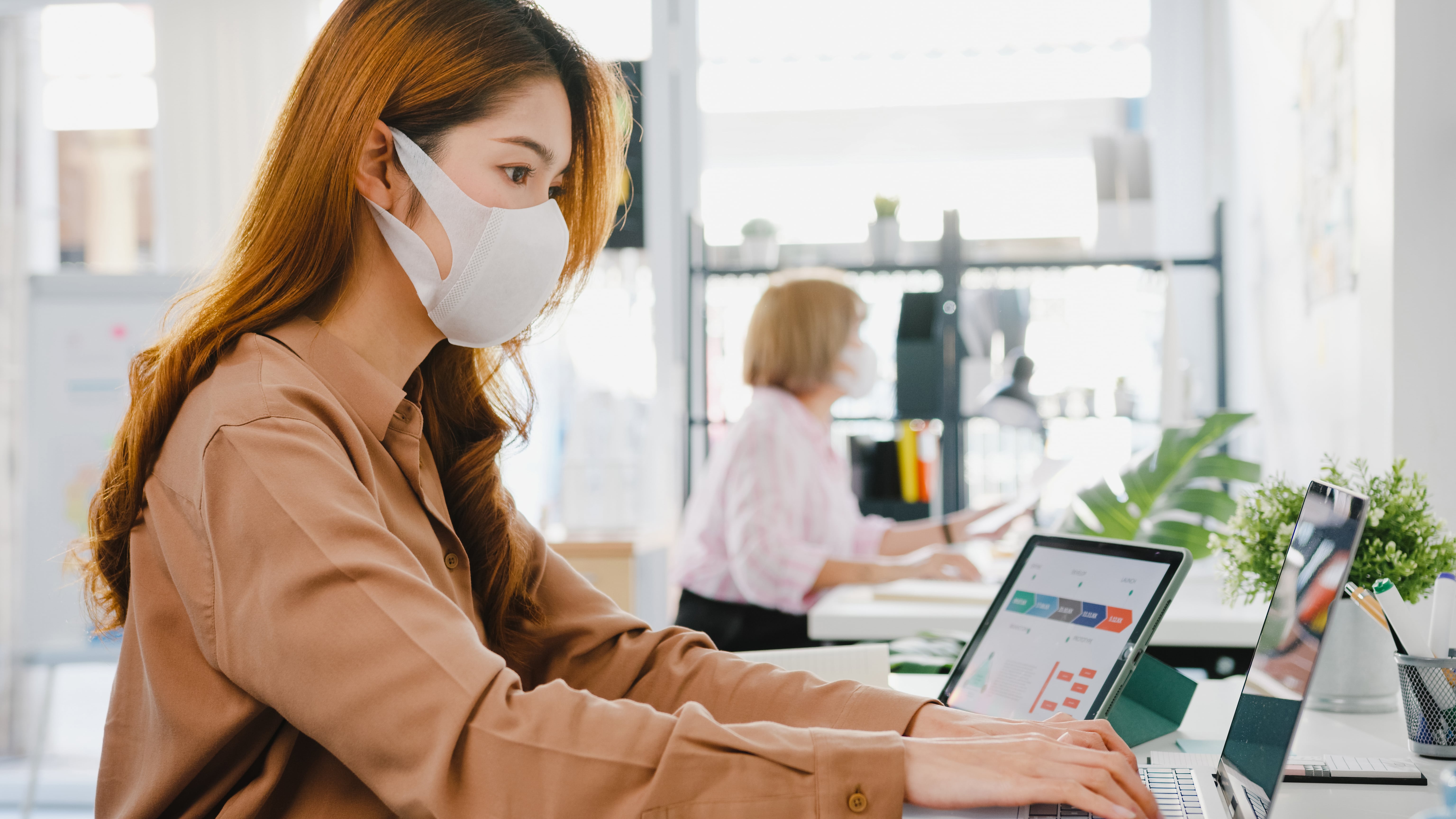 asia-businesswoman-entrepreneur-wearing-medical-face-mask-social-distancing-new-normal-situation-virus-prevention-while-using-laptop-back-work-office-min